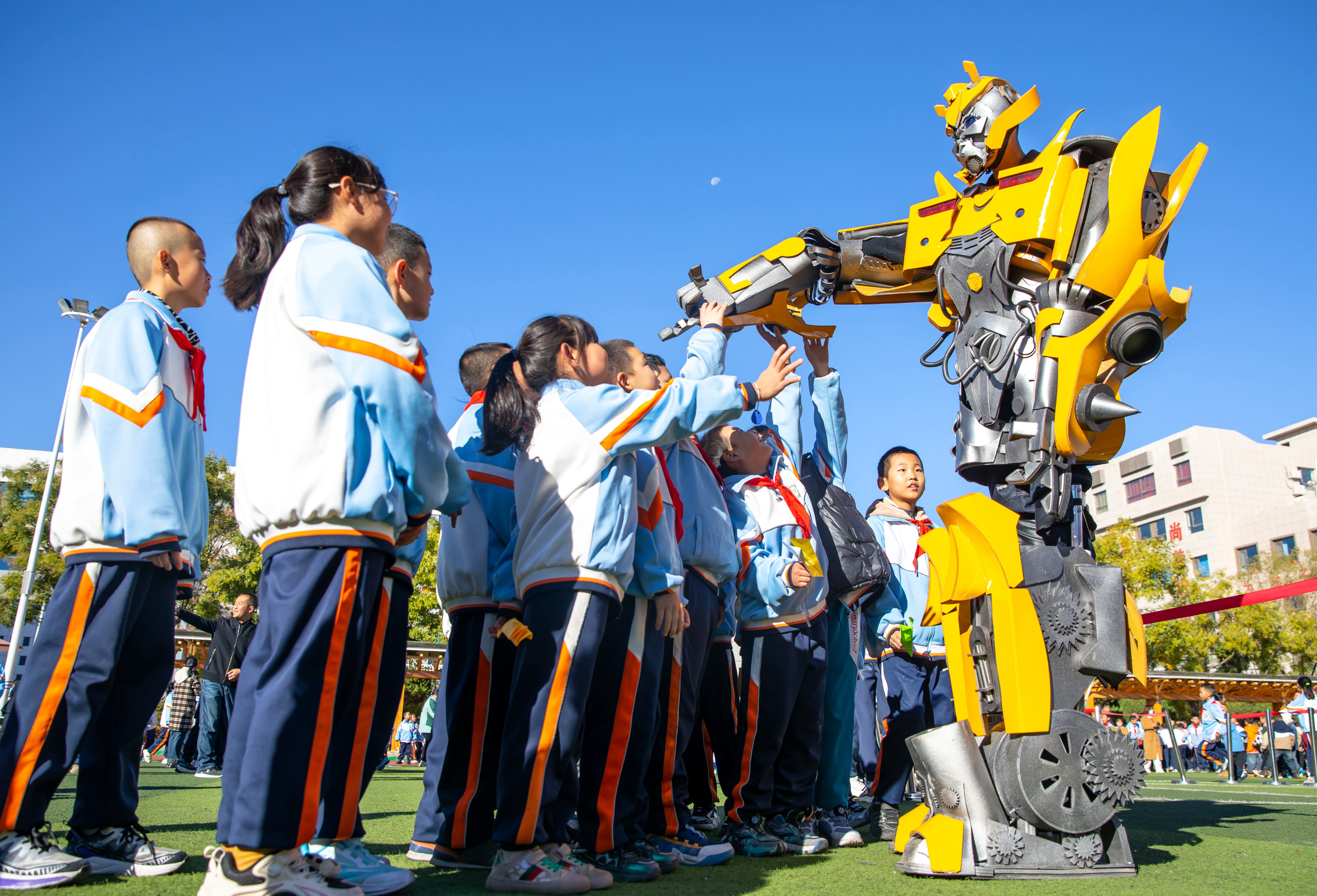 2024年10月22日，在甘肅省張掖市甘州區(qū)北街街小學(xué)科技大篷車嘉年華活動上，學(xué)生與“大黃蜂”機器人互動。楊瀟 攝.jpg