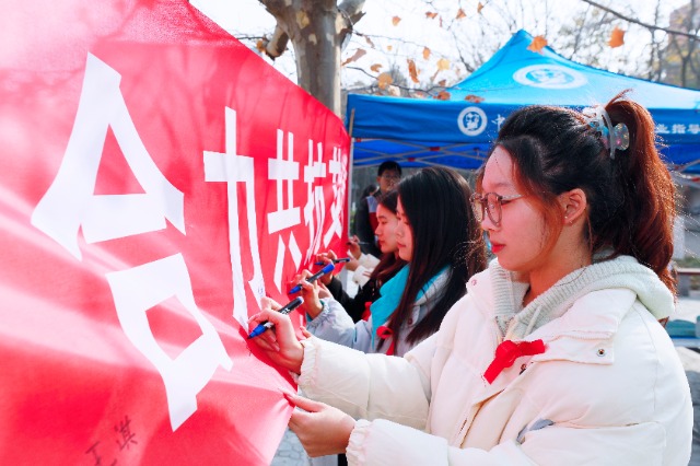 20231127中國石油大學(xué)（華東）青年學(xué)子在合力共抗艾滋的條幅上簽字，表達(dá)抗擊艾滋病的決心和信心  .jpg