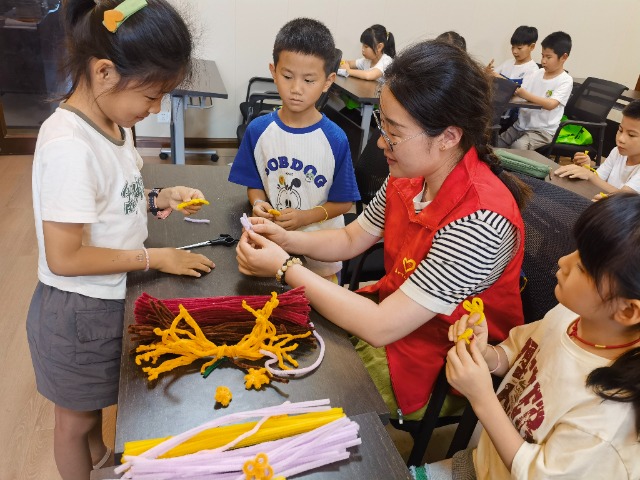 7月12日，在泰州市海陵區(qū)城東街道林湖社區(qū)，泰州市大浦小學(xué)“綠葉”暑期公益班的老師正在教孩子們一起做手工2（拍攝者：泰州市大浦中心小學(xué)  陳惠婷）.jpg